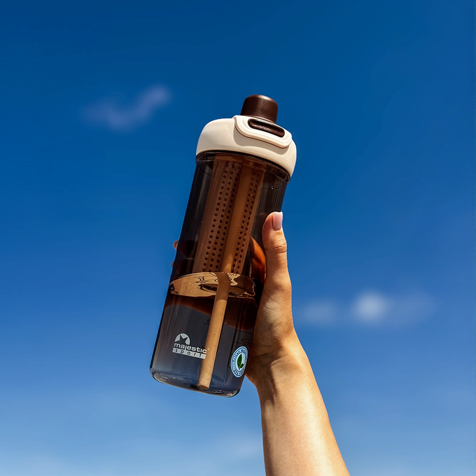 Kobieta trzyma kawową butelkę tritanową na wodę na tle nieba, Majestic Sport Zoya