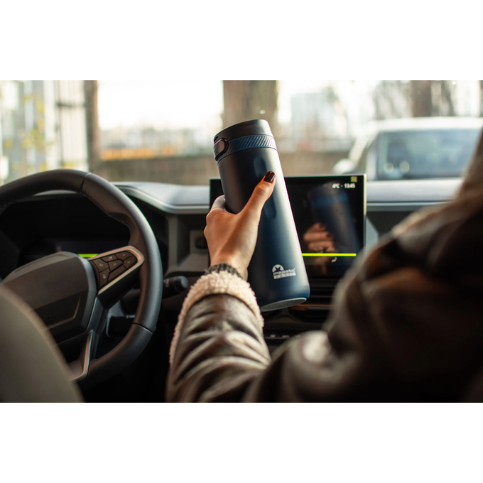 Kobieta w samochodzie na miejscu pasażera trzyma niebieski kubek termiczny z logotypem Majestic Sport