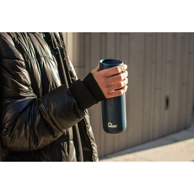 Mężczyzna na spacerze w mieście trzyma niebieski kubek termiczny z logotypem Majestic Sport Nord