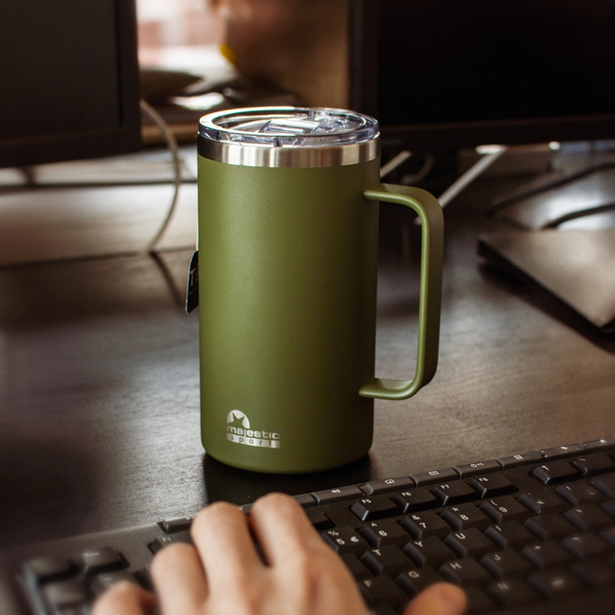 Mężczyzna trzyma w dłoni zielony kubek termiczny z uchwytem, Majestic Sport Gump, idealny na ciepły napój