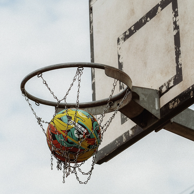 Piłka do koszykówki, Majestic Sport Arrow multicolor, w środku siatki do koszykówki na boisko outdoorowym